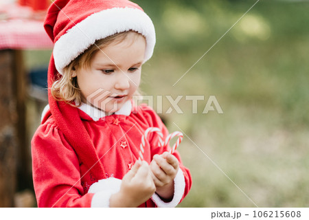 Christmas in july. Child waiting for Christmas in wood in summer. portrait of little girl in red dress decorating christmas tree. winter holidays and people concept. Merry Christmas and Happy Holidays 106215608
