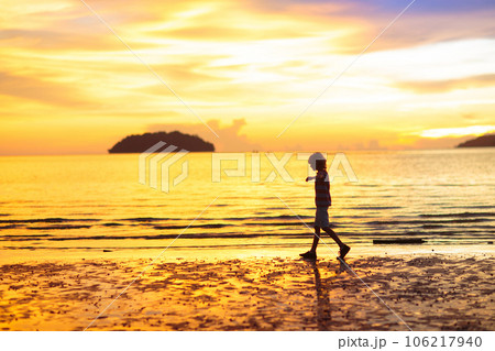 Child playing on ocean beach. Kid at sunset sea. 106217940