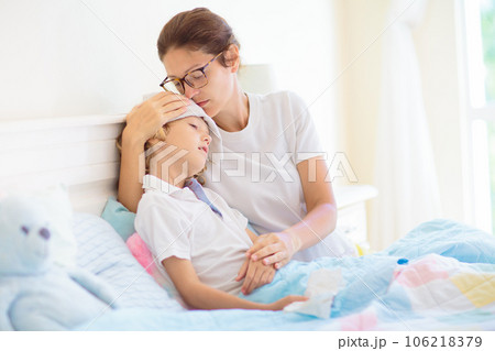 Sick child in bed. Mother checking on unwell kid. 106218379