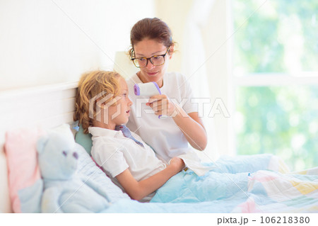 Sick child in bed. Mother checking on unwell kid. Sick child in bed. Mother checking on unwell kid. 106218380