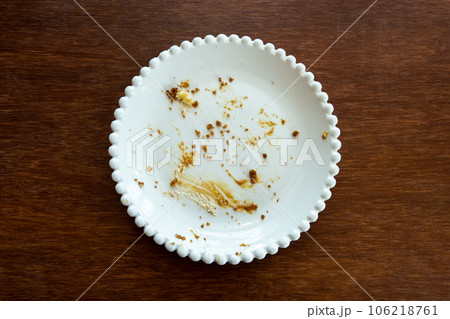 Empty plate with crumbs after eating on a wooden background. The concept of the end of the holiday or celebration. Nearby place for text. 106218761