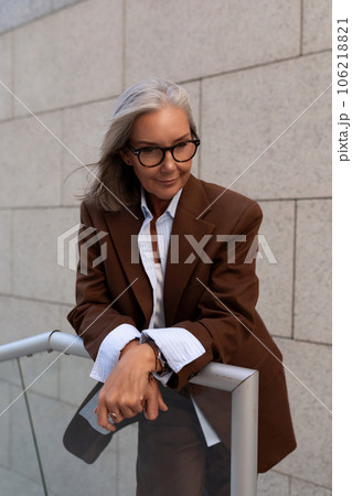 close-up of a slender well-groomed pretty gray-haired business woman pensioner standing on the porch close-up of a slender well-groomed pretty gray-haired business woman pensioner standing on the porch 106218821