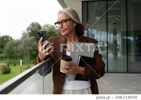 confident mature old lady with gray hair in glasses wearing a brown jacket is waiting for a business 106219040