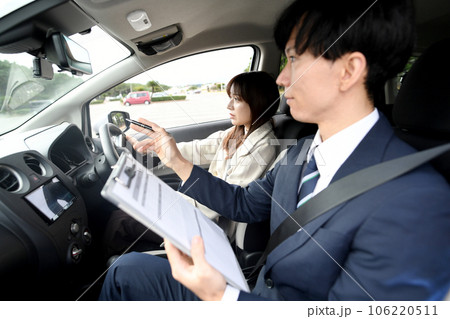 車の運転教習をする男性教官と女性生徒 車の運転教習をする男性教官と女性生徒 106220511