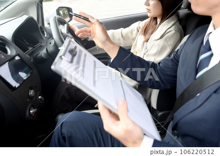車の運転教習をする男性教官と女性生徒 106220512