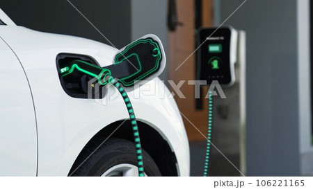 Electric car plugged in with home charging station. Peruse Electric car plugged in with home charging station. Peruse 106221165
