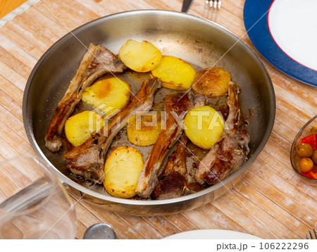 Seared and roasted lamb ribs served with baked potato on table, top view. 106222296