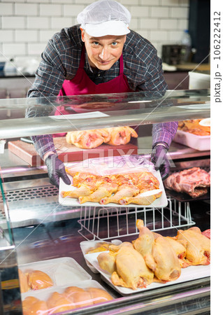 Adult man puts chicken meat in showcase Adult man puts chicken meat in showcase 106222412