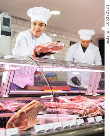 Female butcher choosing slice of raw veal sirloin for customer Female butcher choosing slice of raw veal sirloin for customer 106222521