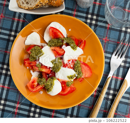 Caprese salad with mozzarella, tomatoes and pesto sauce on plate Caprese salad with mozzarella, tomatoes and pesto sauce on plate 106222522