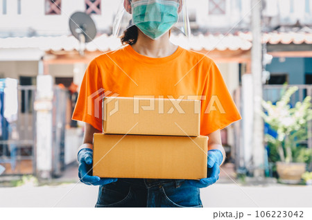 Delivery service courier holding boxes mail for sending to customer while wearing mask and glove for protect herself in covid-19 pandemic outbreak. 106223042