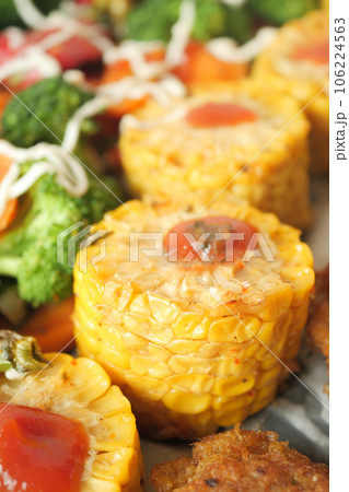 Ears of corn baked with herbs on white baking paper 106224563