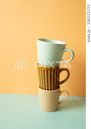 Stack of mug cup on mint green table. orange wall background. copy space 106225253