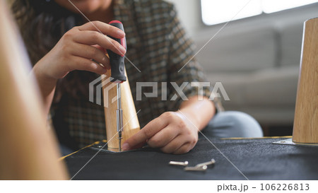Women use screwdriver equipment to tighten screw while assembling leg of chair to making furniture 106226813