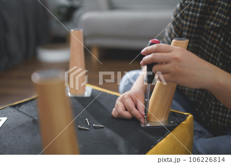 Women use screwdriver equipment to tighten screw while assembling leg of chair to making furniture Women use screwdriver equipment to tighten screw while assembling leg of chair to making furniture 106226814
