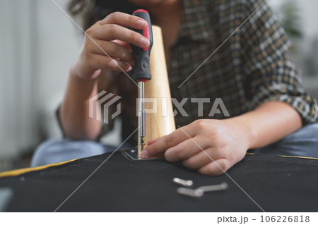 Women use screwdriver equipment to tighten screw while repairing leg of chair and making furniture 106226818