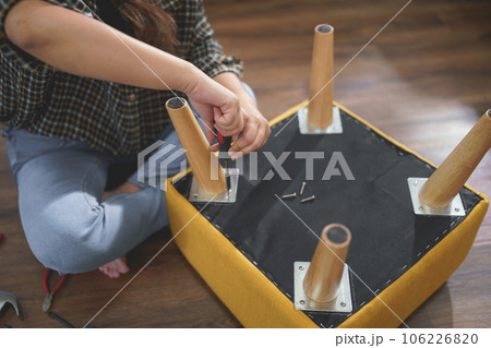 Women use screwdriver equipment to tighten screw while repairing leg of chair and making furniture Women use screwdriver equipment to tighten screw while repairing leg of chair and making furniture 106226820