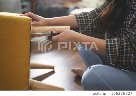 Women tighten screw with screwdriver equipment for assembling leg of chair and making furniture Women tighten screw with screwdriver equipment for assembling leg of chair and making furniture 106226827