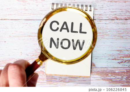 Call now text seen through magnifying glasses on a notepad 106226845