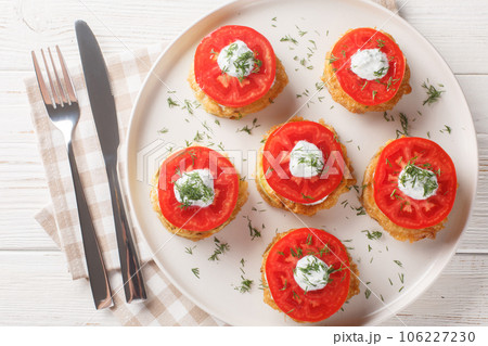 Fried zucchini with tomato, dill, mayonnaise and garlic sauce close-up in a plate. Horizontal top view 106227230