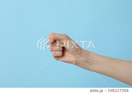 Female hand clenched into a fist on a light blue background Female hand clenched into a fist on a light blue background 106227306