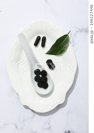 Tablets of activated carbon in a white spoon 106227446