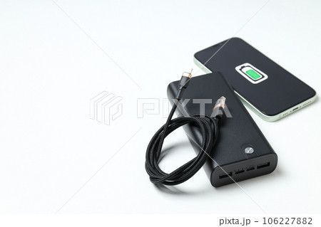Powerbank, smartphone and cord on white background, space for text 106227882