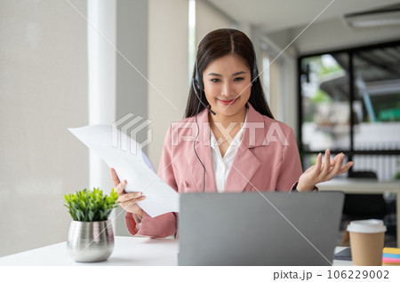 A female call-centre agent in headset is having a conversation with a customer A female call-centre agent in headset is having a conversation with a customer 106229002