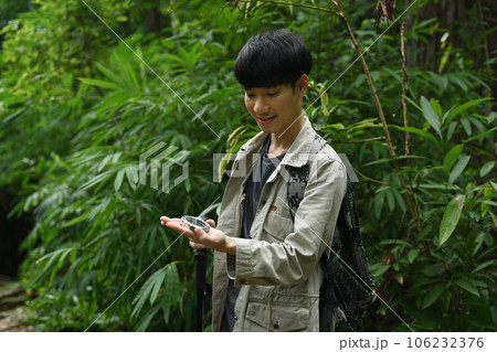 Male hiker using compass for directions in the forest, enjoying his active vacation Male hiker using compass for directions in the forest, enjoying his active vacation 106232376