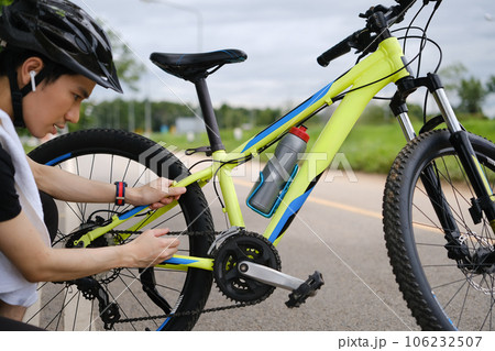 Asian male cyclist fixing his bicycle in the park in the summer day. Sport, emotions and healthy lifestyle 106232507