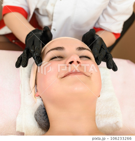 Relaxing and tension-relieving facial massage in the cosmetology room of the spa salon 106233266