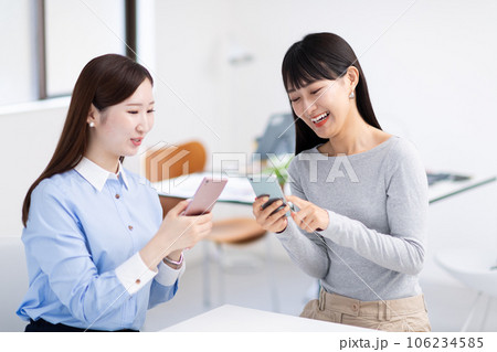 スマホを見せ合う女性・手元 106234585
