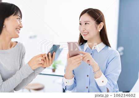 スマホを見せ合う女性・手元 106234602