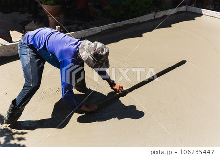 Workers level cement concrete concrete patio floor using long trowel. 106235447