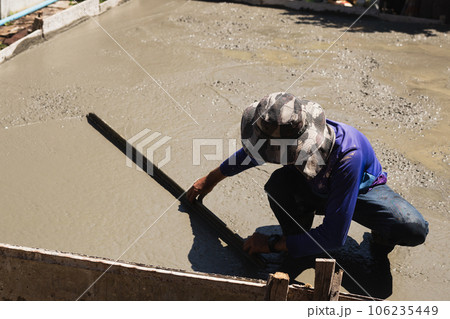 Workers level cement concrete concrete patio floor using long trowel. Workers level cement concrete concrete patio floor using long trowel. 106235449
