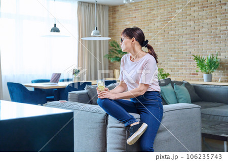 Mature woman drinking glass of water with lemon ice 106235743