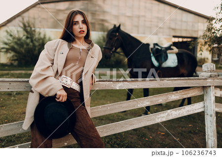 Cowgirl in brown clothes with her horse at outdoors ranch Cowgirl in brown clothes with her horse at outdoors ranch 106236743