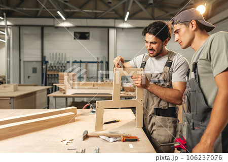 Two young men carpenters making furniture in warehouse of wood factory Two young men carpenters making furniture in warehouse of wood factory 106237076
