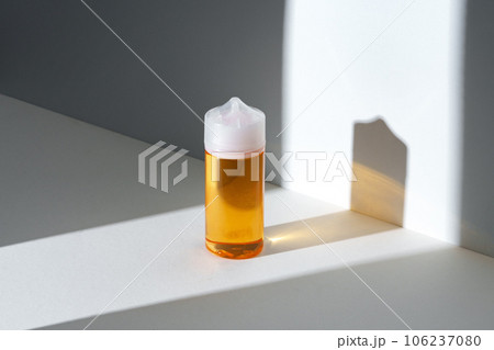 Dropper bottle with vape liquid on white background in the sunlight with shadows Dropper bottle with vape liquid on white background in the sunlight with shadows 106237080