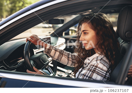 Portrait of a beautiful smiling woman in a car looking out of the window 106237107