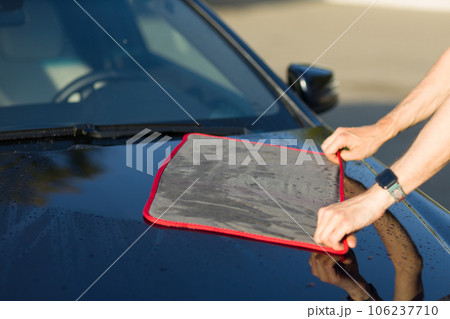 Worker washing car at car wash and wipe vehicle with microfiber towel rag 106237710