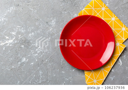 Top view on colored background empty round red plate on tablecloth for food. Empty dish on napkin with space for your design Top view on colored background empty round red plate on tablecloth for food. Empty dish on napkin with space for your design 106237936