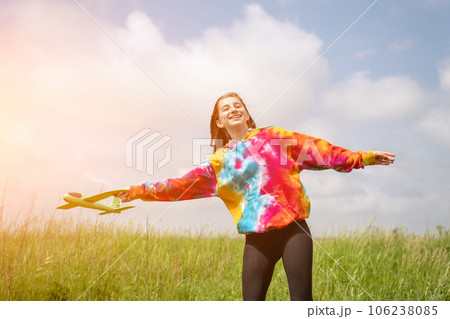 Beautiful girl playing with toy plane outdoors in the field. Teenager female person launching airplane at the nature. Concept of freedom and imagination Beautiful girl playing with toy plane outdoors in the field. Teenager female person launching airplane at the nature. Concept of freedom and imagination 106238085