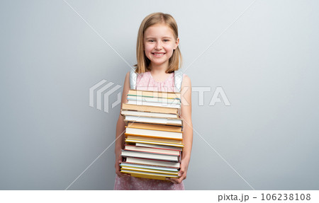 Little girl with backpack and textbooks stack on gray background 106238108