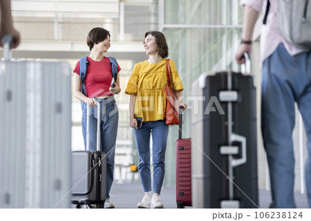 キャリーバッグを持って歩く2人の若い女性　海外旅行・空港　イメージ 106238124