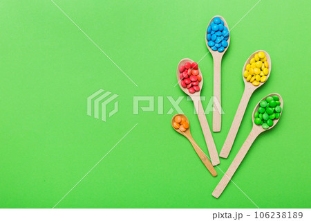 delicious colorful sweet candies on spoon on colored background . Confectionery decor top view with copy space delicious colorful sweet candies on spoon on colored background . Confectionery decor top view with copy space 106238189