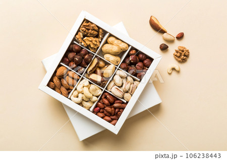 Various varieties of nuts lying in paper box on table background. Top view. Healthy food. Close up, copy space, top view, flat lay. Walnut, pistachios, almonds, hazelnuts and cashews 106238443