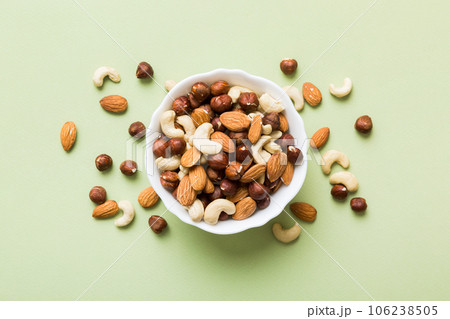Assortment of nuts in wooden bowl on colored table. Cashew, hazelnuts, walnuts, almonds. Mix of nuts Top view with copy space 106238505