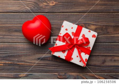 gift box with red bow and red heart on colored background . Top view. Flat lay gift box with red bow and red heart on colored background . Top view. Flat lay 106238506