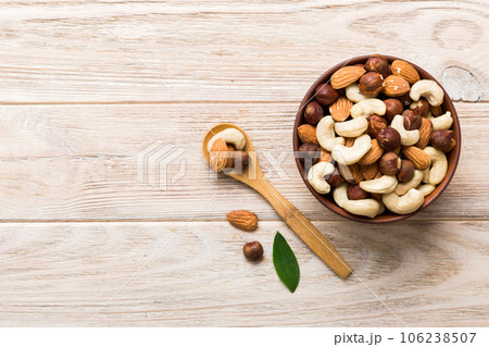 Assortment of nuts in wooden bowl on colored table. Cashew, hazelnuts, walnuts, almonds. Mix of nuts Top view with copy space Assortment of nuts in wooden bowl on colored table. Cashew, hazelnuts, walnuts, almonds. Mix of nuts Top view with copy space 106238507